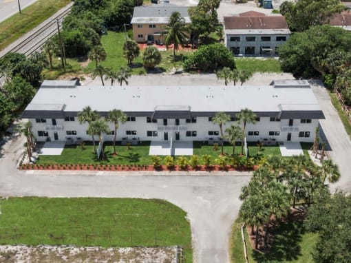 an aerial view of an apartment complex with palm trees and grass