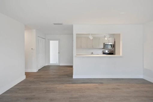 an empty living room and kitchen with white walls and wood floors