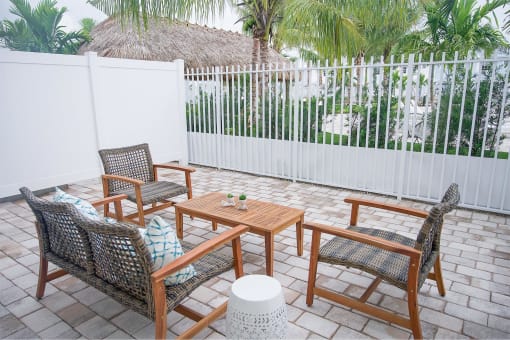 A patio with a table and chairs in front of a white fence