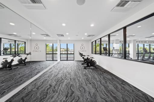 A gym with exercise machines and windows in a building