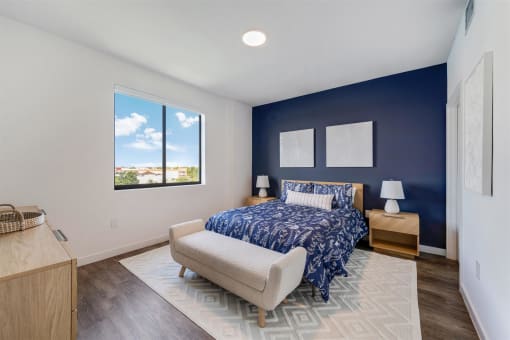 A bedroom with a bed and a blue wall and a window