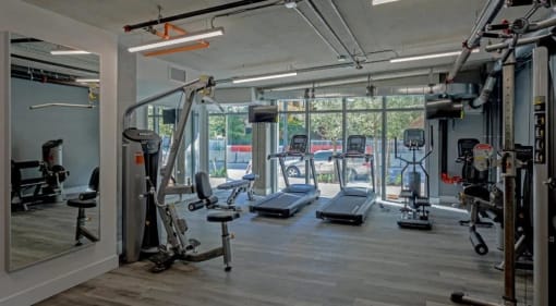 a gym with cardio equipment and windows in a building