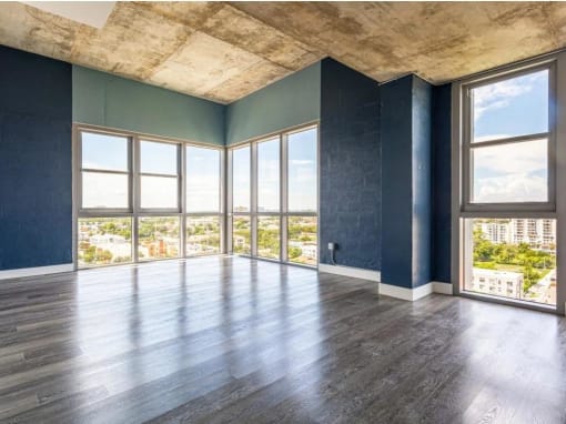 an empty living room with windows and a wood floor