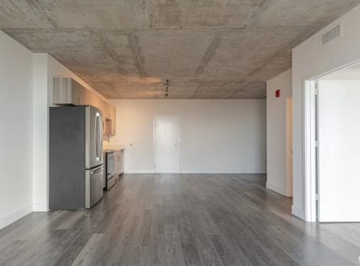 an empty living room with a stainless steel refrigerator