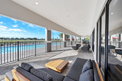 a living room with a couch and a balcony overlooking a swimming pool