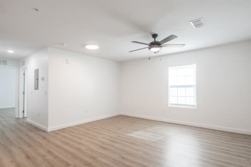 an empty living room with white walls and a ceiling fan