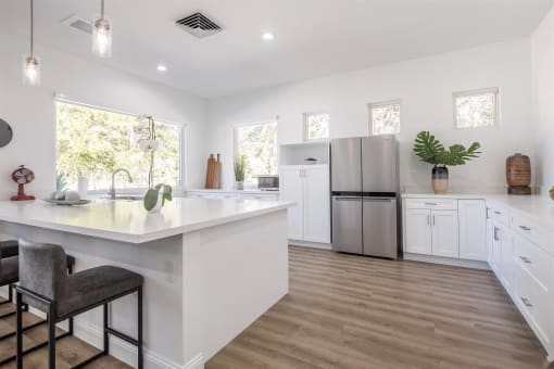 a large white kitchen with white cabinets and a stainless steel refrigerator