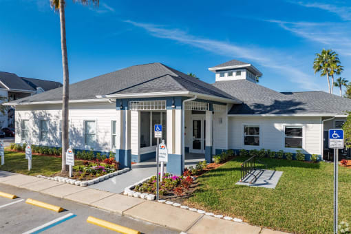 the front of a white house with palm trees and a sidewalk