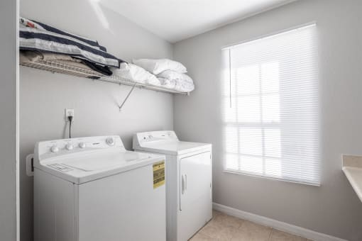 a white washer and dryer in a room with a window and a sink