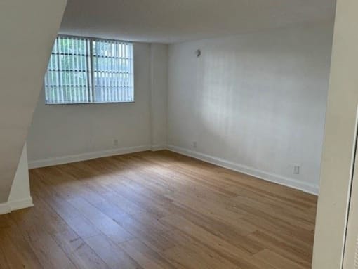 an empty living room with wood floors and a window