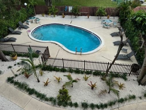 an aerial view of a pool with chairs and palm trees
