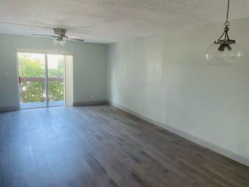 an empty living room with a ceiling fan and a window