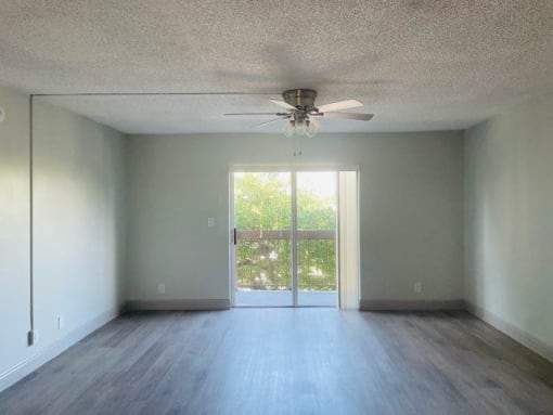 an empty living room with a ceiling fan