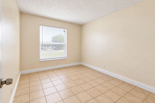 A room with a window and tiled floor.