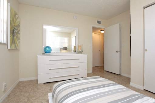 A bedroom with a bed, dresser, and mirror.