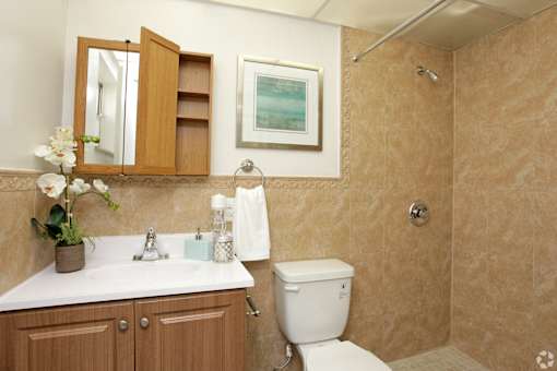 A bathroom with a toilet, sink, and a mirror.