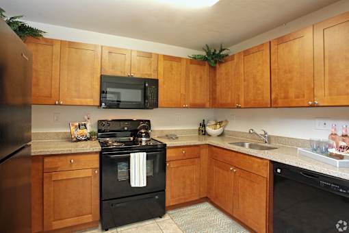 A kitchen with wooden cabinets and black appliances.