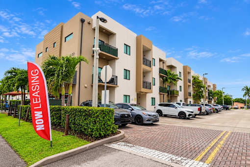 A building with a red sign that says "NOW LEASING" in front of it.