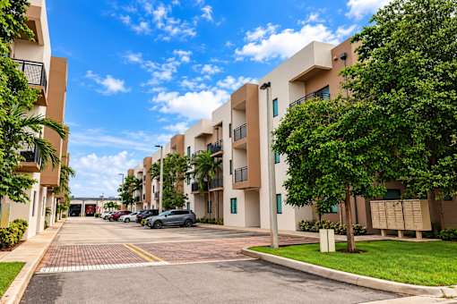 A sunny day at a residential complex with cars parked in the driveway.