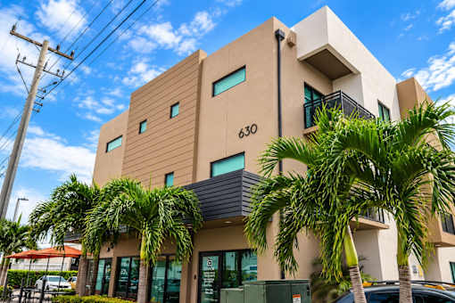 A modern building with palm trees in front.