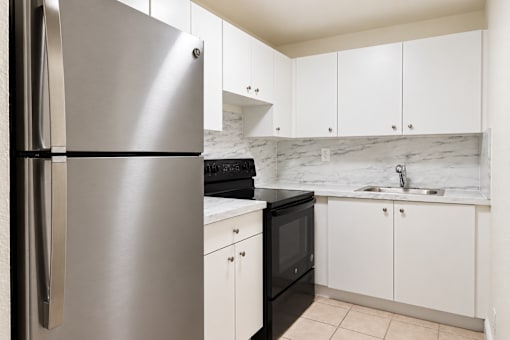 A modern kitchen with a stainless steel refrigerator and black oven.
