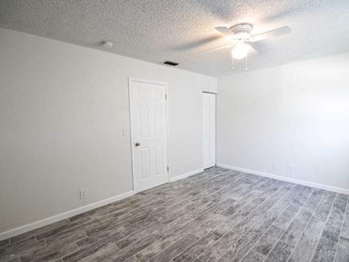 an empty living room with a ceiling fan and a white door