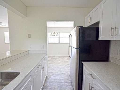 an empty kitchen with white cabinets and a black refrigerator