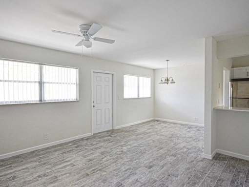 an empty living room with a ceiling fan and a window