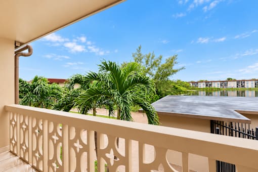 A balcony with a white railing and a view of a building and trees.