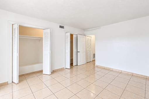 A white room with tiled floors and three open doors.