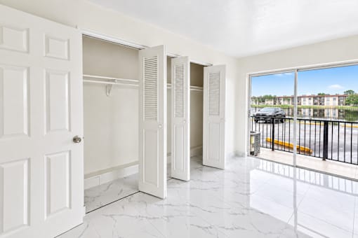 A white door is open to a hallway with marble floors.