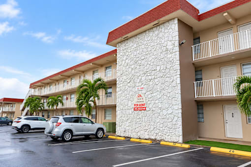 A building with a red roof and a sign that says "For Rent" on the side of it.