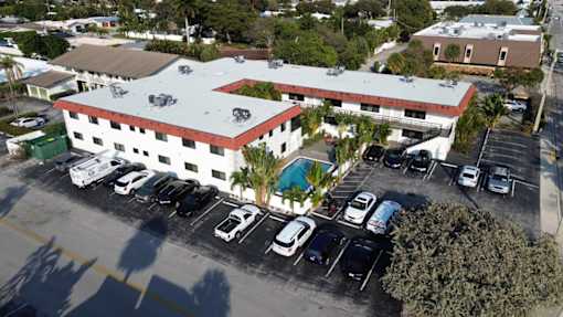 A parking lot with a white building with a red roof.