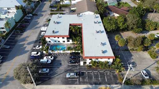 A parking lot with a building and a pool in the background.