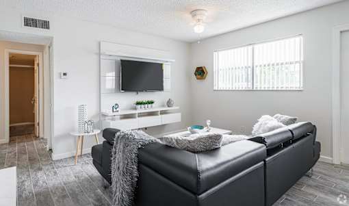 A black leather sofa with a grey throw blanket on it in a living room.