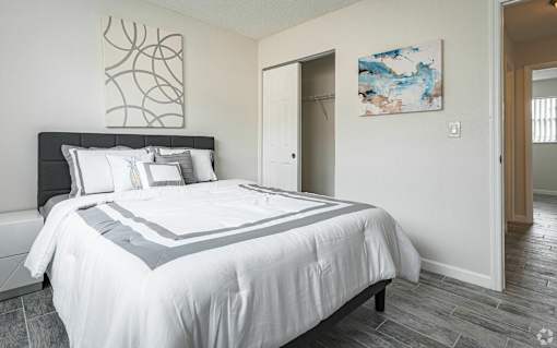 A bedroom with a large bed and a painting on the wall.