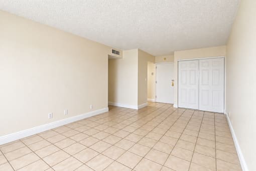 A room with beige walls and tile flooring with a white door.