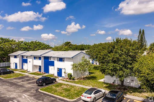A parking lot with cars and a building with blue doors.