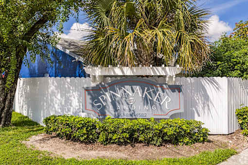 A white building with a sign that says Spinnaker Landing and a phone number.