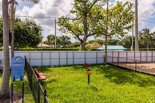 A blue sign with a tree on it is next to a red bench.