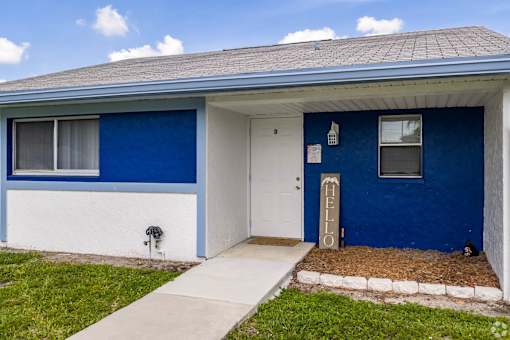 A blue and white house with a white door and a window.