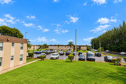 A sunny day at a parking lot with cars and a building in the background.