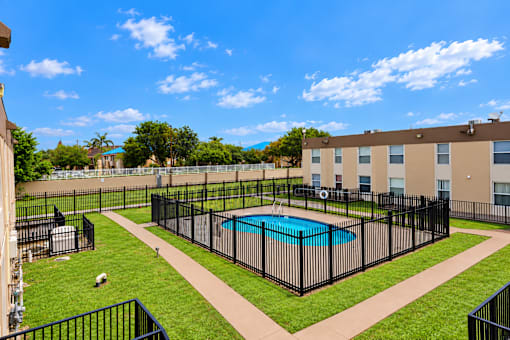 A black fenced in area with a pool in the middle.