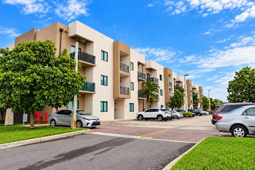 A row of modern apartment buildings with cars parked in front.
