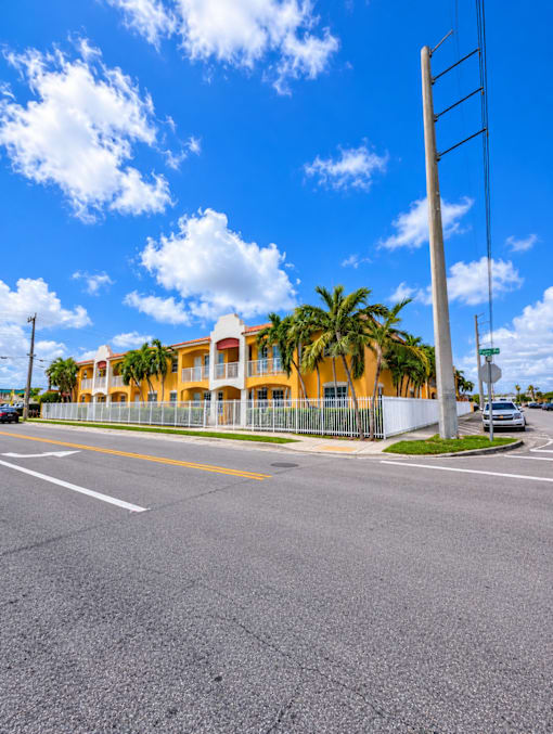 A street view with a building and palm trees.