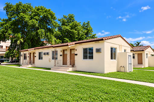 A row of houses with green lawns in front.