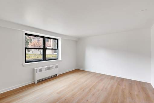 A room with a window and a radiator on the floor.