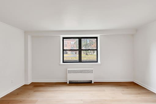 A room with a window and a radiator on the floor.