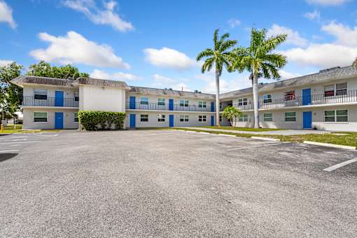 A parking lot in front of a white building with blue trim.