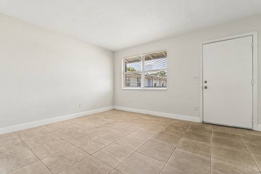 A room with a white door and a window showing a view of a building outside.